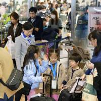 Travelers returning from their New Year\'s holidays crowd the arrival lobby at Haneda Airport in Tokyo on Sunday. | KYODO