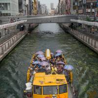 A cruise boat plies the murky waters of Dotonbori canal. | STEPHEN MANSFIELD