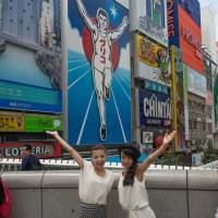 In the running for fun: Visitors pose on Ebisu Bridge before the iconic Glico Man sign. | STEPHEN MANSFIELD