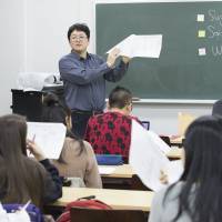 Tak Watanabe, an assistant professor in the Faculty of Liberal Arts, explains to students participating in the SAIMS program how to prepare presentations during a class in the \"Introduction to Trans-Disciplinary Human Development\" course. | MASANORI DOI