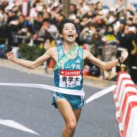 Aoyama Gakuin\'s Toshinori Watanabe crosses the finish line in Tokyo\'s Otemachi district on Sunday as his school defended its Hakone Ekiden title. | KYODO