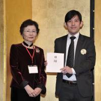 The Japan Times Deputy Sales Officer Yusuke Numata (right) holds a donation to The Japan Times Readers\' Fund received from President of Ikebana International Tokyo Founding Chapter Noriko Kira at the Palace Hotel Tokyo on Jan. 26. | YOSHIAKI MIURA