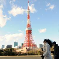Dog-walkers pass Tower Tokyo in the capital\'s Minato Ward on Wednesday. The ward plans to introduce new building regulations to preserve the few remaining full views of the much-loved tower. | SATOKO KAWASAKI