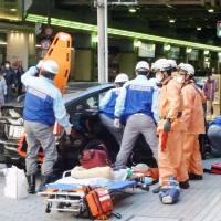 Ambulance staff rush to the scene where a car mowed down pedestrians on a sidewalk in the Umeda district of Osaka on Thursday. | KYODO