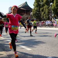 A Tokyo Marathon runner gets a high five of supporter near Zojo-ji Temple in Tokyo on Sunday. | MARK THOMPSON