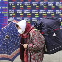 An elderly woman passes a stock price display in Tokyo on Monday. The Nikkei\'s leap of 1,069 points on the day was one of its best ever. | AP