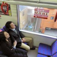 A couple ride the Keikyu Love Train in one of four nonreserved box seats decorated with heart designs, in Tokyo on Monday. The special Keikyu Corp. train, launched to promote Valentine\'s Day on Feb. 14, will run through White Day on March 14, the Tokyo-based railway said. | KYODO