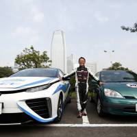 Toyota Motor Corp. President Akio Toyoda stands between the Mirai fuel cell-powered vehicle (left) and a first-generation Prius hybrid vehicle ahead of the 44th Tokyo Motor Show last October. | BLOOMBERG