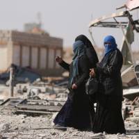 Women walk in the war-ravaged town of al-Shadadi in Hasaka province, northeast Syria, on Friday. | REUTERS