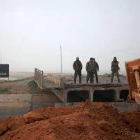 Syrian government forces look at a bridge broken by Islamic State group fighters connecting the village of al-Tiba with Aleppo\'s thermal power plant on the eastern outskirts of the Syria\'s northern embattled city of Aleppo after they retook the area Monday. | AFP-JIJI