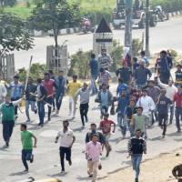 Protestors run along a street during violence after rival caste groups clashed during a mass rally over access to jobs and education in the district of Rohtak, in northern India, on Friday. Four dead in protests for caste benefits in northern India