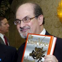 Author Salman Rushdie poses with his 1988 book \"The Satanic Verses\" alongside fellow honoree Tashbih Sayyed before the American Jewish Conference\'s 30th Annual Dinner, \"Profiles in Courage: Voices of Muslim Reformers in the Modern World,\" in Beverly Hills, California, in 2006. Iranian state-run media outlets have added $600,000 to a bounty for the killing of Rushdie imposed in 1989 over the publishing of \"The Satanic Verses.\" | REUTERS