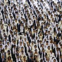 Newlywed couples attend a mass wedding ceremony of the Unification Church at Cheongshim Peace World Centre in Gapyeong, South Korea, on Saturday. | REUTERS