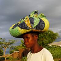 Malawian subsistence farmer Louise Abele carries corn she bought to feed her family near Lilongwe on Jan. 31. | REUTERS