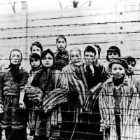 Children standing behind barbed wire in Auschwitz are photographed just after the camp\'s liberation by the Soviet Army in Poland in January 1945. | AP