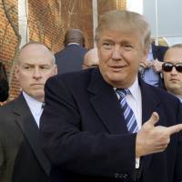 U.S. Republican presidential candidate Donald Trump points at a supporter at a polling station for the presidential primary in Manchester, New Hampshire, on Tuesday. | REUTERS