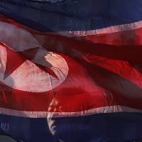 A North Korean man carries his country’s national flag at the Pyongyang Indoor Stadium in the nation’s capital on Feb. 16. Money trail shows China middlemen at heart of North Korea’s illicit cash-flow network