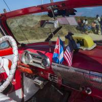 The stars and stripes and the Cuban national flag are placed together on the dashboard of a vintage American convertible in Havana Thursday. President Barack Obama said that he will visit Cuba on March 21-22, making him the first sitting president in more than half a century to visit the island nation. | AP