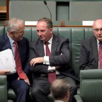 Australian Prime Minister Malcolm Turnbull (left) speaks to Australian Agriculture Minister Barnaby Joyce (center) as Federal Minister for Infrastructure and Regional Development Warren Truss sits next to them in the House of Representatives at Parliament House in Canberra on Thursday. Joyce was elected leader of the Nationals party the same day, automatically making him deputy prime minister. | REUTERS
