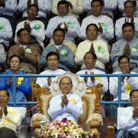 Myanmar President Thein Sein (behind flowers) is seen in a June 2013 file image. The military ruler advocated a slow pace of reforms, although critics say that left corruption unchallenged. | AFP-JIJI