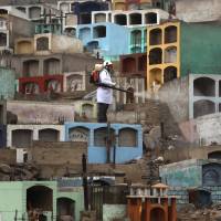 A health worker fumigates the Martires 19 de Julio cemetery to help prevent the breeding of mosquitoes that can carry the Dengue, Chikungunya and Zika viruses, on the outskirts of Lima on Tuesday. | AP