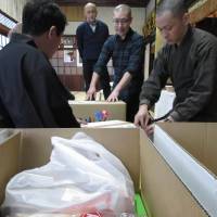Monks pack snacks given as offerings at Kuonji Temple in Nagoya on Feb. 2 to deliver to impoverished children. | CHUNICHI SHIMBUN