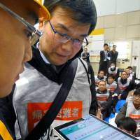 Participants use a translation app on a tablet computer during an earthquake drill in Tokyo on Monday. | KYODO