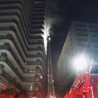 Firefighters work to put out a fire at Forus Tower Tokorozawa, a high-rise condo in Saitama Prefecture, on Monday night. | KYODO