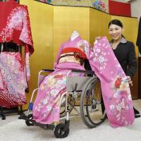 Akiko Nakajima, head of Hanayome Kobo in Kasugai, Aichi Prefecture, shows a kimono that can be put on without standing up. | KYODO