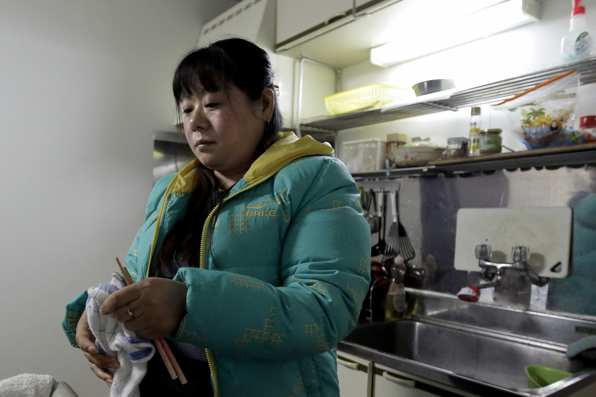 Chinese trainee Tang Xili wipes her chopsticks in a building housing a local labor union office and a shelter for Chinese trainees managed in Hashima, Gifu Prefecture, on Jan. 14. | BLOOMBERG