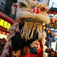 A reveler performs a lion dance outside a restaurant during Chinese Lunar New Year celebrations in Chinatown in Yokohama on Monday. | REUTERS