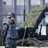 A Self-Defense Force member stands by a PAC-3 Patriot missile unit deployed at the Defense Ministry in Tokyo on Sunday ahead of an anticipated North Korean rocket launch. | AP