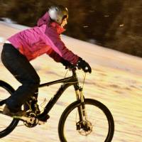 A woman rides a bike with fat tires down a snowy slope at the Togari Onsen ski resort in Iiyama, Nagano Prefecture, on Jan. 31. | KYODO