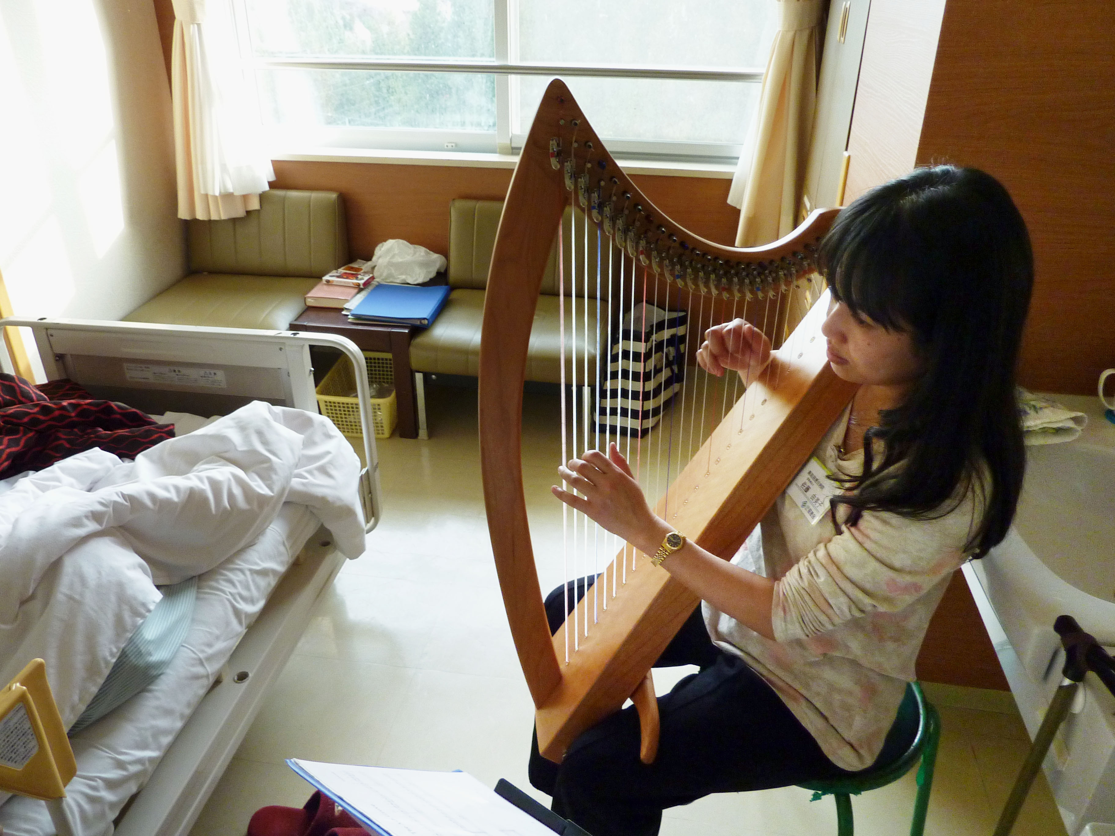 Music therapist Yumiko Sato plays for a bed-ridden patient at Aomori Jikeikai Hospital in Aomori on Oct. 7. | KYODO