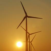 In this photo taken in October 2012, the sun rises behind wind turbines in Nauen, near Berlin, Germany. | AP