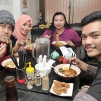 Endy Harmoko (left), a student at Yokohama National University, enjoys a bowl of ramen with his family from Indonesia  at Naritaya in Tokyo’s Asakusa district on  Feb. 22. | YOSHIAKI MIURA