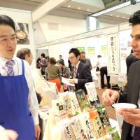 A vendor talks to a visitor at the Japan Halal Expo in Chiba’s Makuhari Messe in November. | COURTESY OF HALAL MEDIA JAPAN