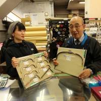 Yoshimi Ichihashi and Kouji Shomoi of Tsunoda hold up a display of their gammaguchi (frog-mouth) purse clasps. | KIT NAGAMURA