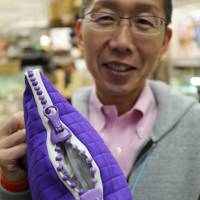Takahiro Kato of K-Fastener holds up a sample of a huge YKK zip. | KIT NAGAMURA