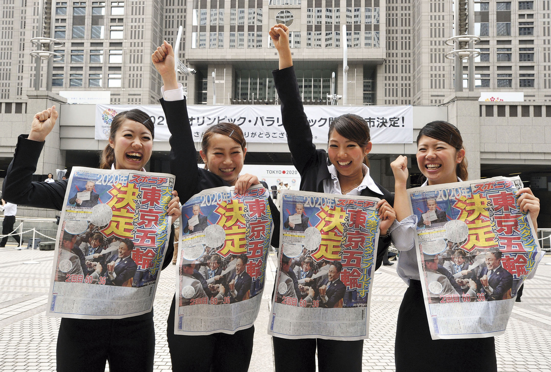 Four cheers: Government workers hold up copies of a newspaper announcing the decision in 2013 to award the 2020 Olympics to Tokyo. Japan's four main newspapers have announced they will be official sponsors for the games, but other publications believe this could affect objective reporting of the event. | YOSHIAKI MIURA