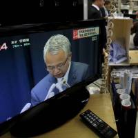 Money matters: A TV broadcasts a news conference in which economy minister Akira Amari announced his resignation. | REUTERS