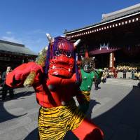 Two parents of kindergarten students dress up as demons, while the children throw beans to ward away evil spirits and bring good luck, as part of the annual Setsubun Festival at Sensoji Temple in Tokyo on Wednesday. | AFP-JIJI