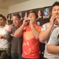 Sunwolves coach Mark Hammett (third from right) eats eho-maki with members of the team during a news conference on Wednesday. | KYODO