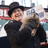 Co-handler Ron Ploucha holds up a weather-forecasting groundhog on Tuesday, the 130th Groundhog Day in Punxsutawney, Pennsylvania. The animal, Punxsutawney Phil, emerged from his burrow and wasn\'t scared back inside by his shadow, thus predicting an early spring. The mock-solemn ceremony is an annual entertainment for Americans shivering through the winter. | REUTERS