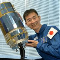 Astronaut Kimiya Yui strikes a pose with a miniature of the Konotori cargo transport vehicle during a news conference Tuesday in Tokyo. Last August, Yui successfully docked the cargo transport to the International Space Station, where he stayed for 141 days before returning to Earth in December. | KYODO