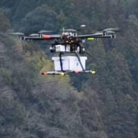 A drone carrying a cargo of eggs and other items is flown in Naka, Tokushima Prefecture, on Wednesday. It was part of a trial by a Tokyo firm that wants to deliver goods via drone in rural areas to cut transportation costs. | KYODO