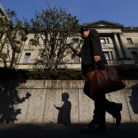 A pedestrian walks past the Bank of Japan headquarters in Tokyo. The central bank this week may discuss whether to exempt &#36;90 billion in short-term funds from its newly imposed negative interest rate. | BLOOMBERG