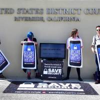 Activists L(from left) uis Nolasco, Aki Rose, Evan Greer and Josh Rabb hold placards reading \"Secure Phones Saves Lives\" during a protest in front of the U.S. District.Court in Riverside, California, on Tuesday. The U.S government\'s decision to delay its effort to force Apple to help unlock an attacker\'s iPhone may only postpone the inevitable drawn-out battle over encryption and data protection. | AFP-JIJI