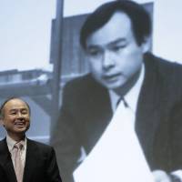 Masayoshi Son, chairman and chief executive officer of SoftBank Group Corp., smiles as a photo from his past is projected in the background at a news conference in Tokyo last month. | BLOOMBERG