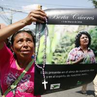 A woman holds up a poster with a photo of slain environmental leader Berta Caceres during a protest march in Tegucigalpa Wednesday. Authorities said that unidentified gunmen killed Nelson Garcia, a colleague of Caceres, who was slain almost two weeks ago in similar circumstances. | AP